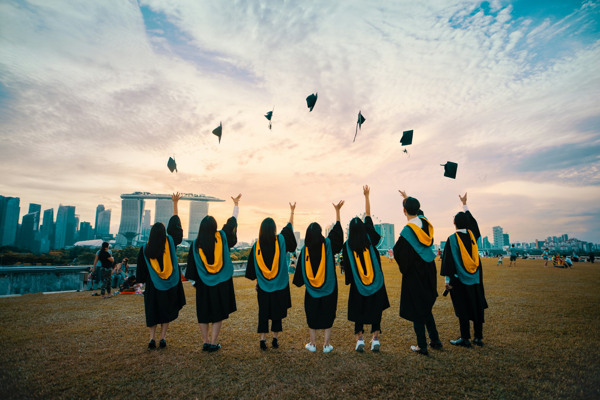 Graduates throwing caps at sunset